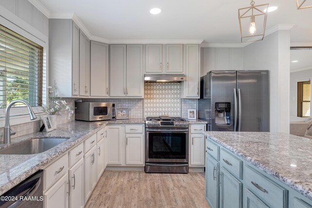 kitchen with light stone countertops, pendant lighting, stainless steel appliances, and sink