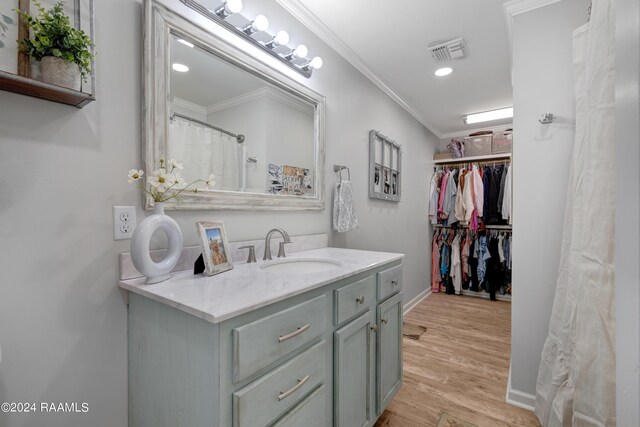 bathroom with wood-type flooring, vanity, and ornamental molding