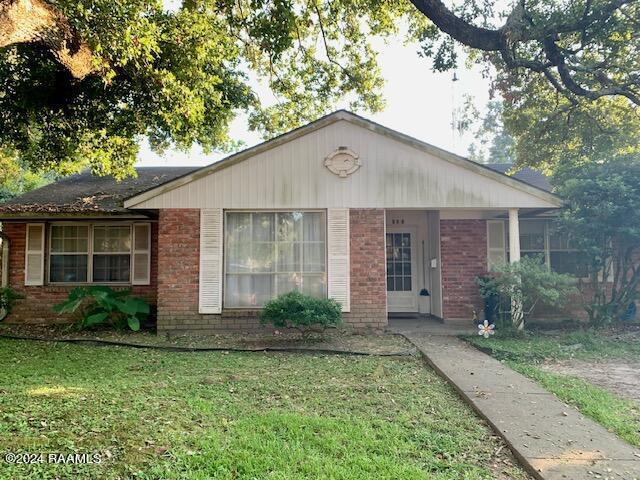 ranch-style house with a front yard and covered porch