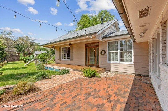 entrance to property featuring a lawn and a patio area