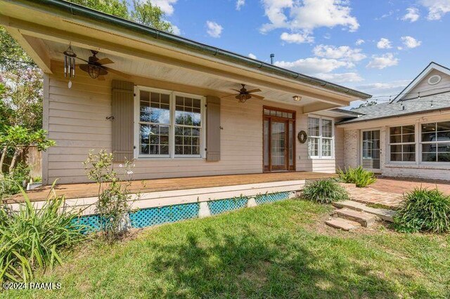 back of property featuring a lawn and ceiling fan