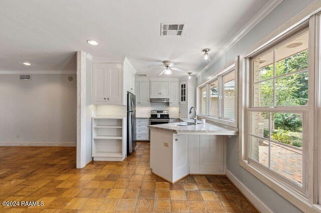 kitchen with appliances with stainless steel finishes, white cabinetry, kitchen peninsula, ceiling fan, and sink