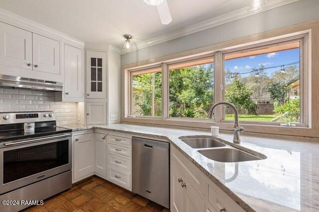 kitchen with light stone counters, sink, white cabinetry, stainless steel appliances, and crown molding