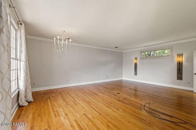 empty room featuring ornamental molding, a chandelier, and hardwood / wood-style flooring