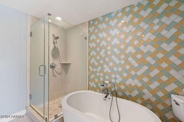 bathroom with shower with separate bathtub, tile walls, and toilet