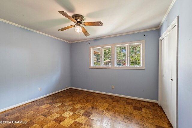 unfurnished bedroom with ceiling fan, a closet, crown molding, and parquet floors