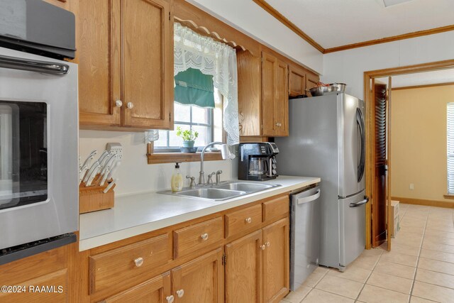 kitchen with crown molding, light tile patterned flooring, stainless steel appliances, and sink