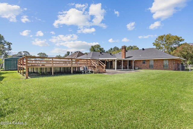 rear view of house featuring a storage shed, a patio area, a yard, and a deck