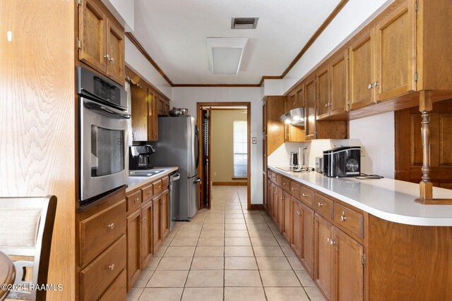 kitchen featuring ornamental molding, light tile patterned floors, kitchen peninsula, and stainless steel appliances