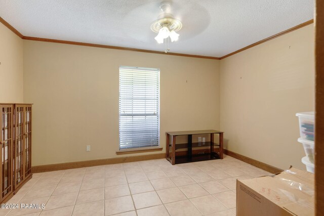 spare room with a textured ceiling, crown molding, ceiling fan, and light tile patterned floors