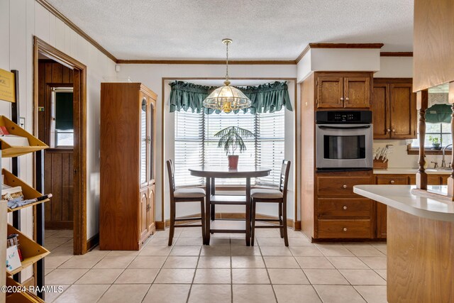 kitchen with pendant lighting, oven, a textured ceiling, and ornamental molding