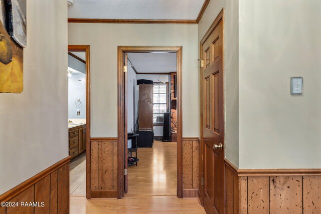 hall featuring a textured ceiling, crown molding, and light wood-type flooring