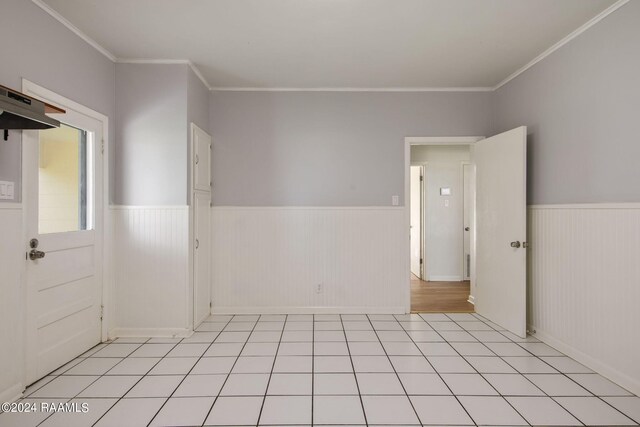 spare room featuring light tile patterned flooring and crown molding