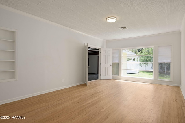 unfurnished room featuring light hardwood / wood-style floors, crown molding, and built in features