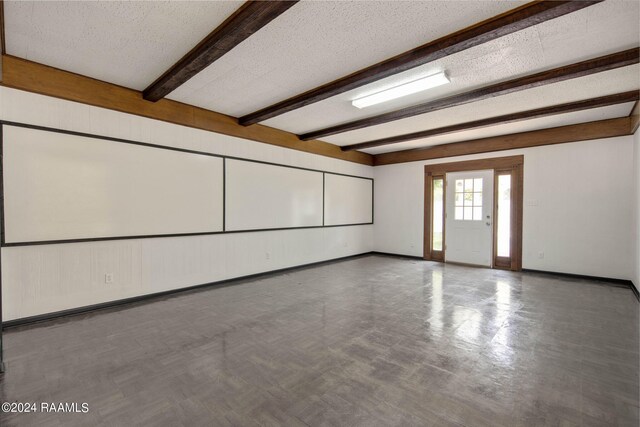 unfurnished room with a textured ceiling and beam ceiling