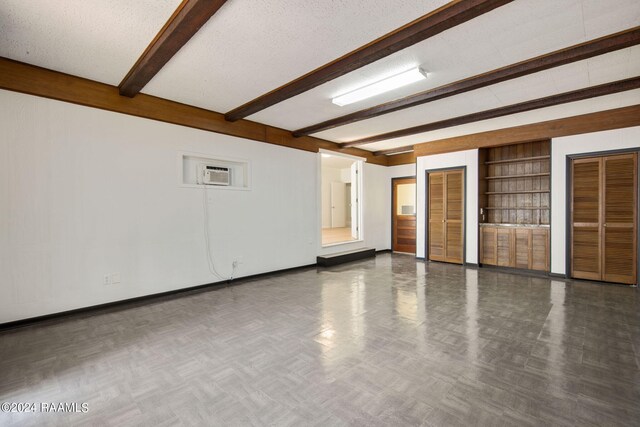 spare room with a textured ceiling, beam ceiling, built in features, and a wall unit AC