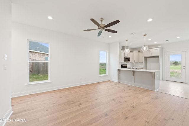 unfurnished living room with light wood finished floors, baseboards, a ceiling fan, and recessed lighting