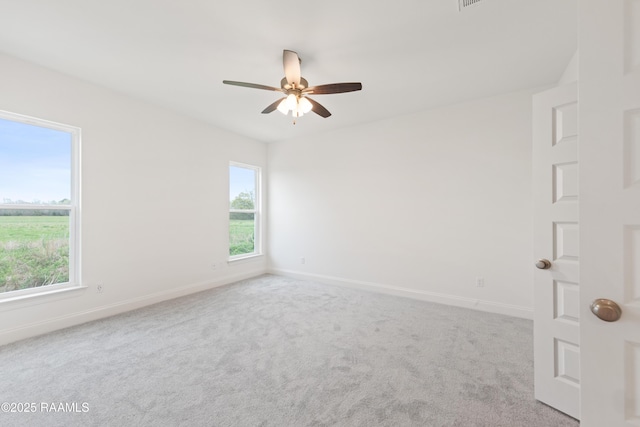 carpeted empty room featuring ceiling fan and baseboards