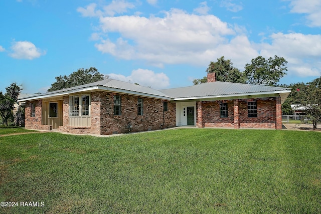 ranch-style house with a chimney, a front lawn, and brick siding