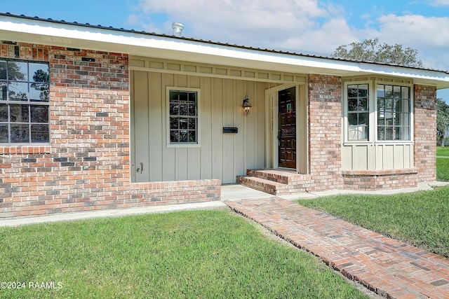 view of exterior entry featuring brick siding and board and batten siding