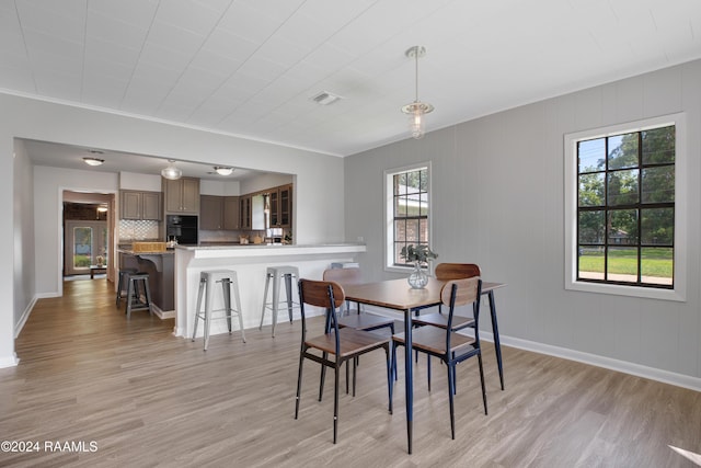 dining room with light wood finished floors, visible vents, and baseboards