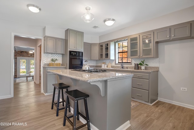 kitchen with a healthy amount of sunlight, oven, stainless steel gas stovetop, and gray cabinetry