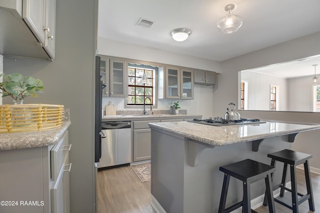 kitchen featuring visible vents, appliances with stainless steel finishes, a breakfast bar, light wood-type flooring, and a sink
