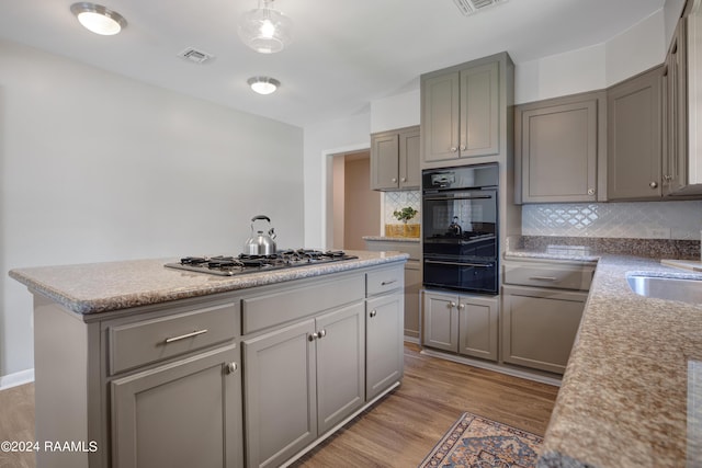 kitchen with a warming drawer, visible vents, stainless steel gas stovetop, gray cabinetry, and black oven