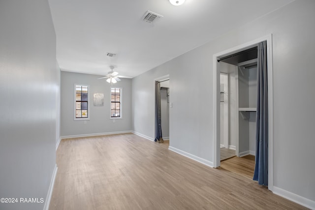 spare room featuring a ceiling fan, visible vents, light wood-style flooring, and baseboards