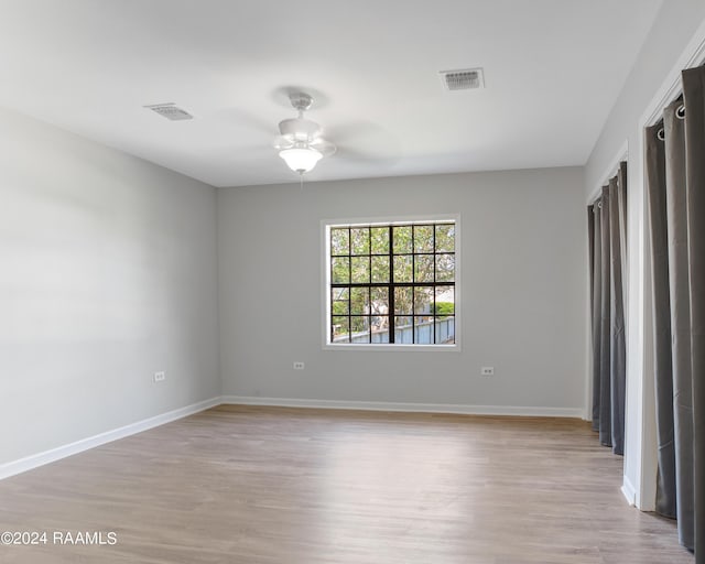 empty room featuring light wood-type flooring, visible vents, and baseboards