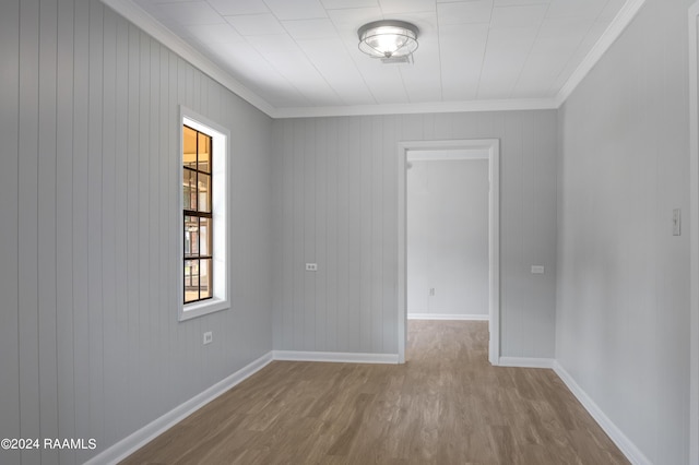 unfurnished room featuring crown molding, baseboards, and wood finished floors