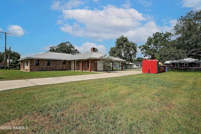 view of front facade with driveway, brick siding, a chimney, and a front yard