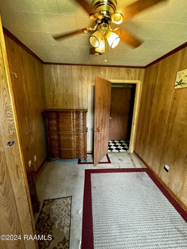 unfurnished bedroom featuring ceiling fan, wooden walls, and crown molding