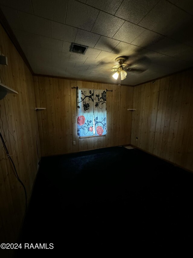 empty room with ceiling fan and wood walls