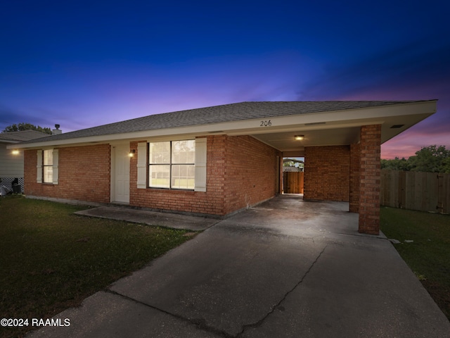 single story home featuring a carport and a lawn