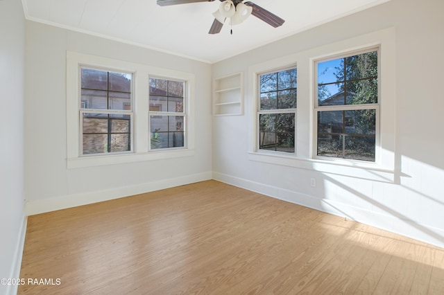 unfurnished room with built in shelves, ceiling fan, ornamental molding, and light wood-type flooring