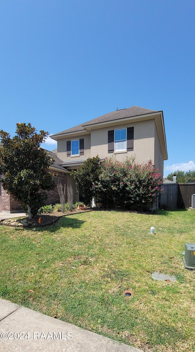 view of front of property with central AC and a front lawn