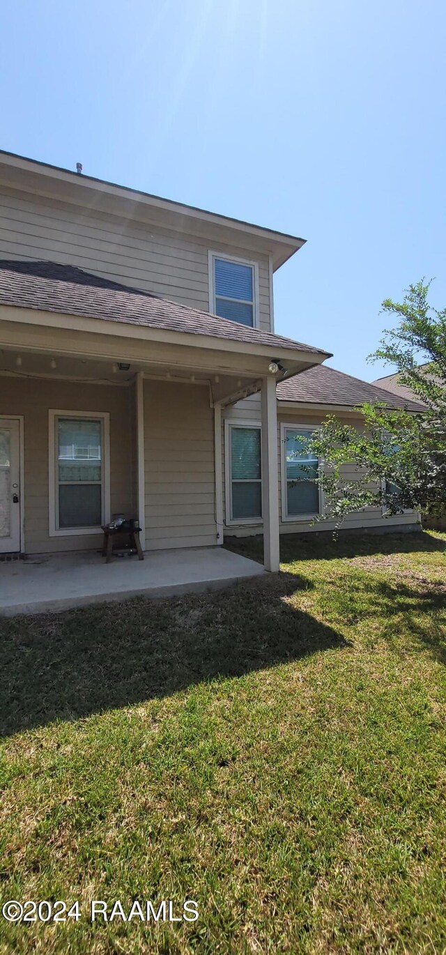 back of property featuring a patio area and a lawn