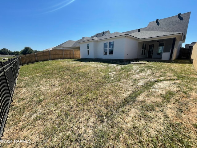 rear view of property featuring ceiling fan and a lawn