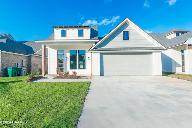 view of front of house featuring covered porch, a garage, and a front lawn