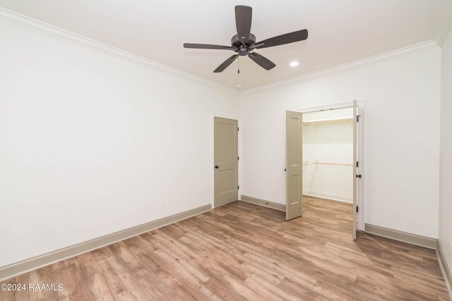 unfurnished bedroom featuring a walk in closet, ceiling fan, crown molding, light hardwood / wood-style floors, and a closet