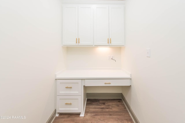 unfurnished office featuring built in desk and dark wood-type flooring