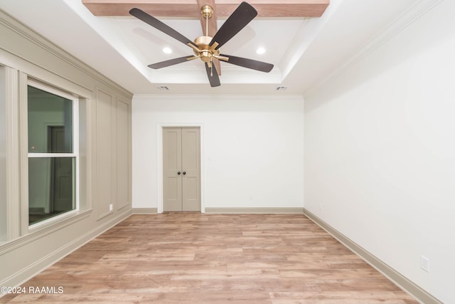 spare room featuring a raised ceiling, ceiling fan, crown molding, and light hardwood / wood-style floors