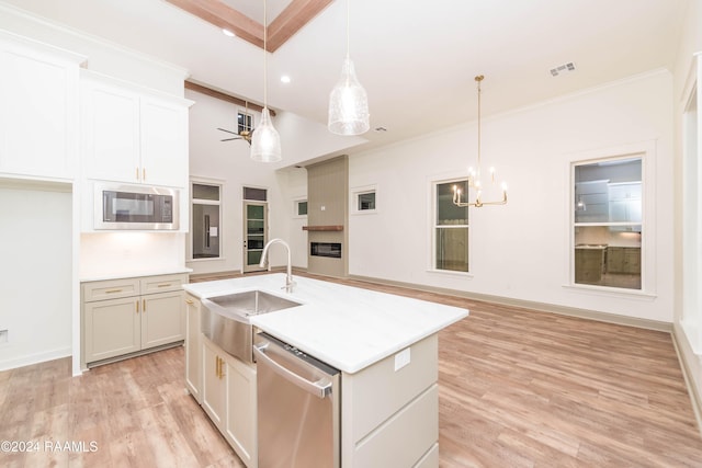 kitchen with built in microwave, hanging light fixtures, stainless steel dishwasher, and a center island with sink