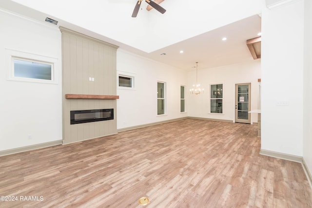 unfurnished living room featuring ceiling fan with notable chandelier, light wood-type flooring, a fireplace, and ornamental molding