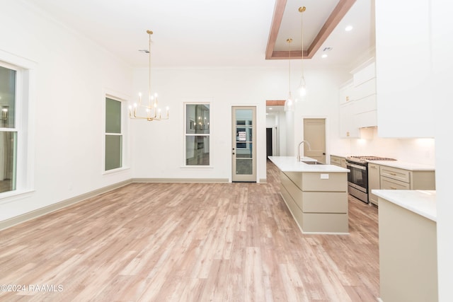 kitchen with pendant lighting, gas stove, light hardwood / wood-style flooring, and an island with sink