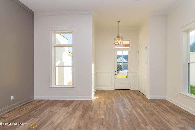 entrance foyer featuring a chandelier, plenty of natural light, and crown molding