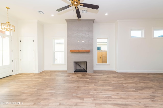 unfurnished living room with ceiling fan with notable chandelier, light wood-type flooring, ornamental molding, and a fireplace