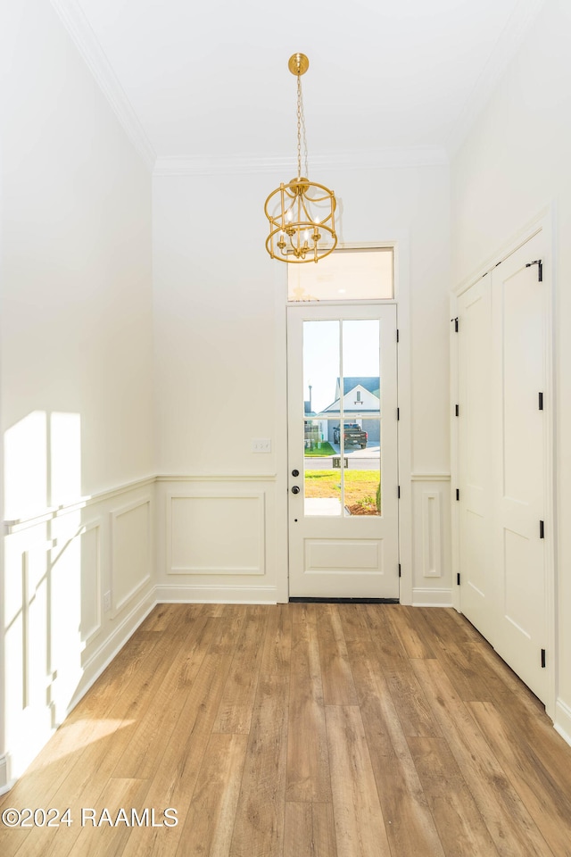 doorway to outside featuring light hardwood / wood-style floors, an inviting chandelier, and ornamental molding