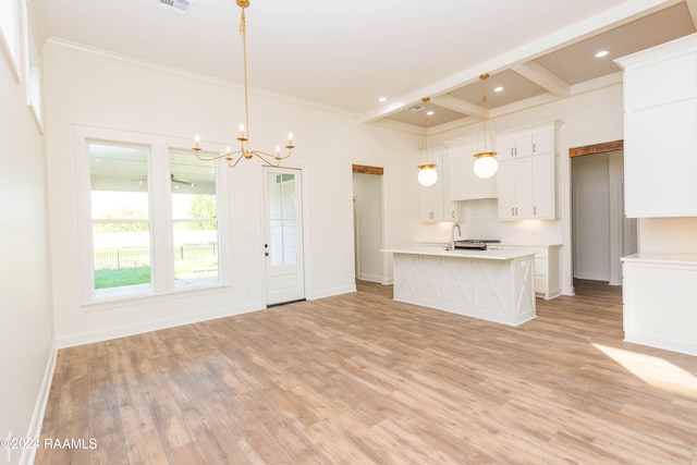 kitchen featuring a kitchen island with sink, white cabinetry, beamed ceiling, and pendant lighting